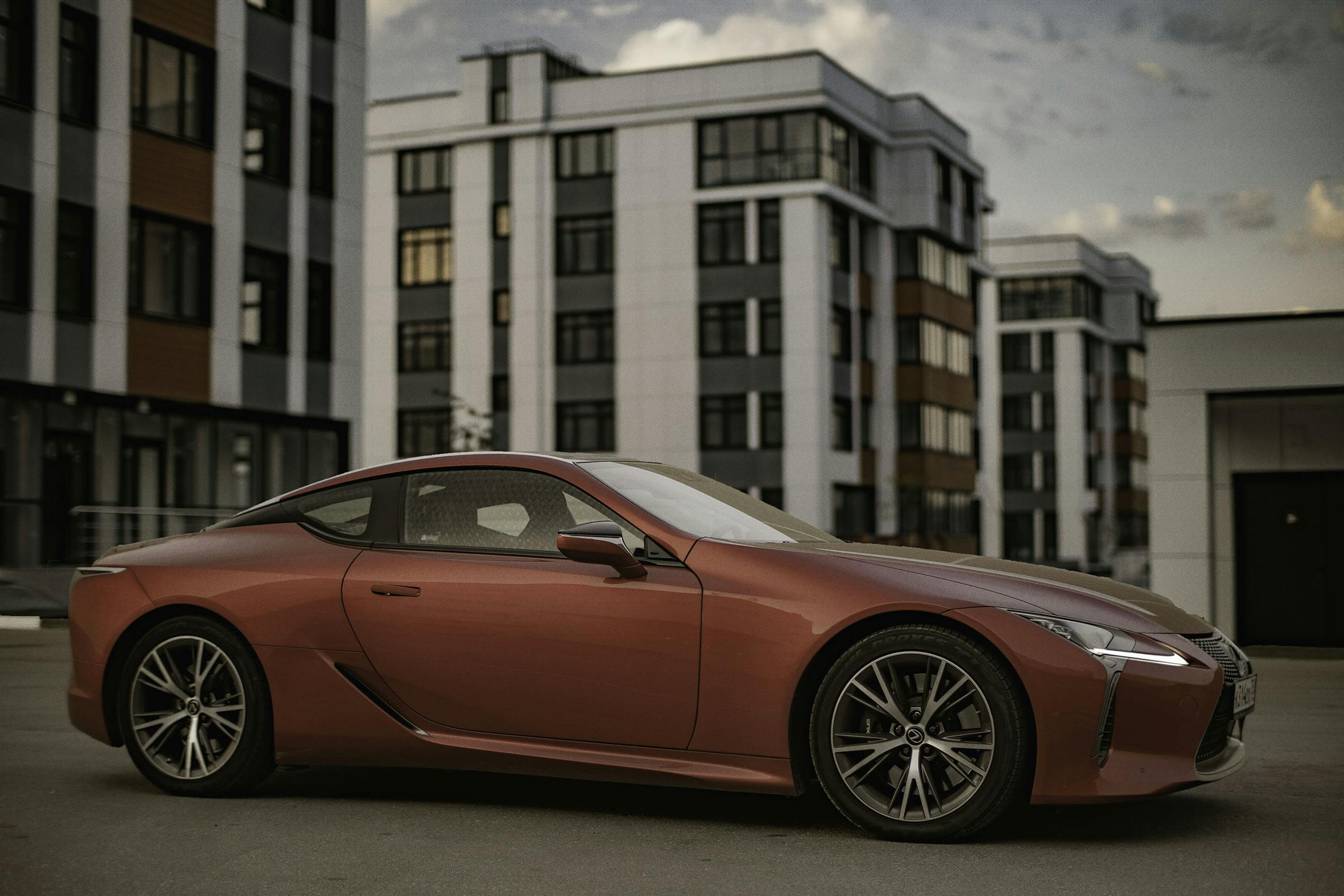 A sleek luxury red sports car is parked in a modern urban area, showcasing elegance and speed.